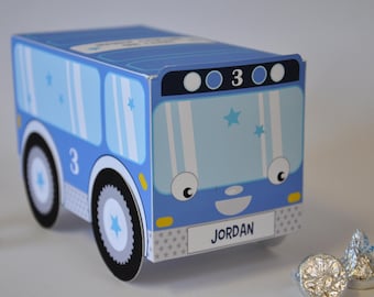 May include: A blue and white cardboard bus favor box with a smiling face, the number 3, and the name "JORDAN" printed on the front.