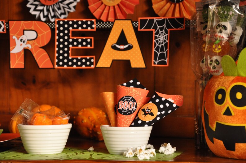 May include: A Halloween party treat table with orange and black decorations, including a banner that reads "Treat", and a pumpkin with a friendly face. There are also small cones filled with popcorn and candy.