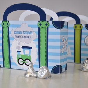 Puede incluir: Cajas de regalo azules y verdes con forma de maleta con un diseño de tren y el texto "Choo Choo! Thanks for chugging by".