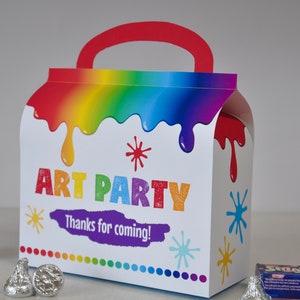 May include: A white cardboard party favor box shaped like a paint can with a red handle. The box has a rainbow paint design with the words "Art Party" and "Thanks for coming!" printed on the front.