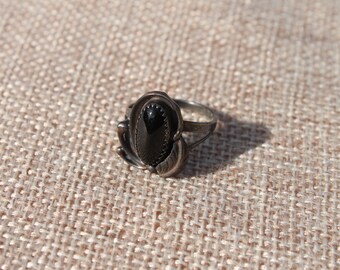 Size 5 3/4 Black Onyx cabochon set in sterling silver ring. Gorgeous 8x13mm oval stone flanked by fancy silverwork. Medium patina!!k.