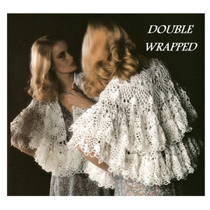 May include: A white crocheted shawl with a double-layered ruffle design. The text "DOUBLE WRAPPED" is printed in black on a white background.