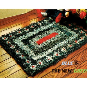May include: A rectangular rug with a blue, black, and white pattern and a red stripe in the center. The rug has a textured appearance and is decorated with small red accents. The text "BLUE IS THE NEW GREEN" is visible on the bottom right.