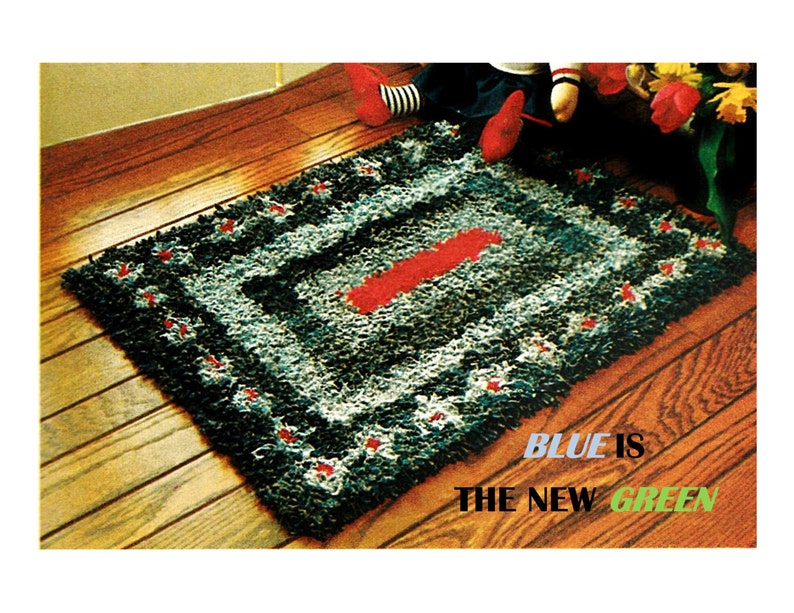 Puede incluir: Una alfombra rectangular con un patr&oacute;n azul, negro y blanco y una franja roja en el centro. La alfombra tiene un aspecto texturizado y est&aacute; decorada con peque&ntilde;os detalles rojos. El texto "BLUE IS THE NEW GREEN" es visible en la parte inferior derecha.