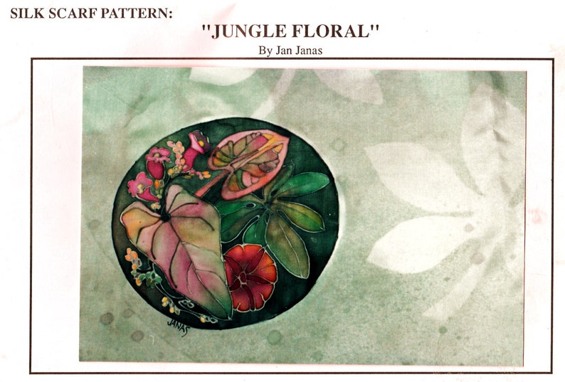 Op de afbeelding: Een zijden sjaalpatroon met de titel "Jungle Floral" van Jan Janas. Het patroon heeft een cirkelvormig ontwerp met roze, groene en rode bladeren en bloemen op een donkergroene achtergrond.