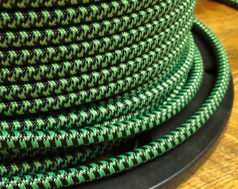 May include: A spool of black and green braided electrical cord. The cord is wound tightly around the spool, creating a textured pattern.