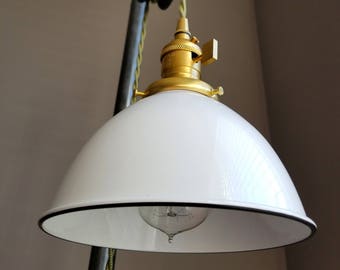 May include: A white industrial style pendant light with a black rim and a gold socket. The light is hanging from a black cord and a pulley system.