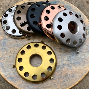 Può includere: Sei anelli per paralumi in metallo diversi con un foro al centro e un motivo decorativo di fori attorno al bordo. Gli anelli sono in diverse finiture, tra cui argento, oro, nero e rame.