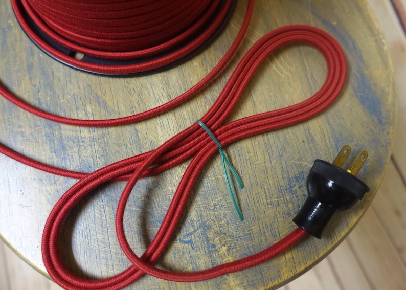May include: Red electrical cord with a black plug. The cord is coiled and tied with a green twist tie.
