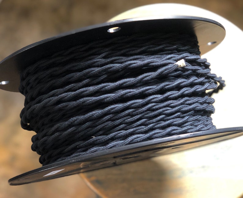 May include: A spool of black twisted electrical cord. The cord is wound around a black plastic spool.