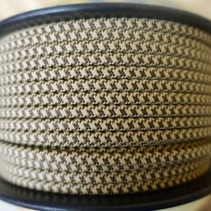 May include: A spool of brown and beige patterned cord. The cord is wound tightly around the spool.