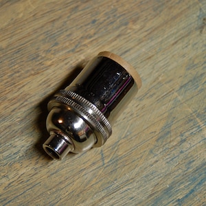 May include: A chrome light bulb socket with a brown cardboard insulator.