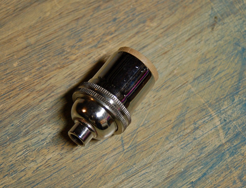 May include: A chrome light bulb socket with a brown cardboard insulator.