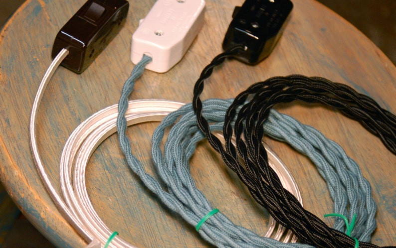 May include: Three spools of electrical cord, one silver, one blue, and one black. The cords are coiled and ready to be used for electrical projects.
