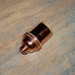 May include: A copper-colored light bulb socket with a threaded base.
