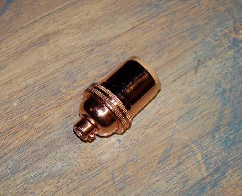 May include: A copper-colored light bulb socket with a threaded base.
