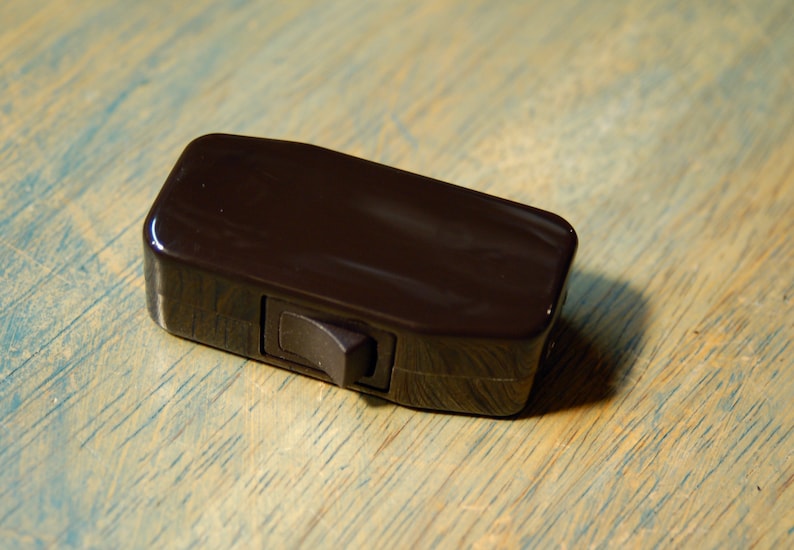 May include: A dark brown inline light switch with a black toggle switch.