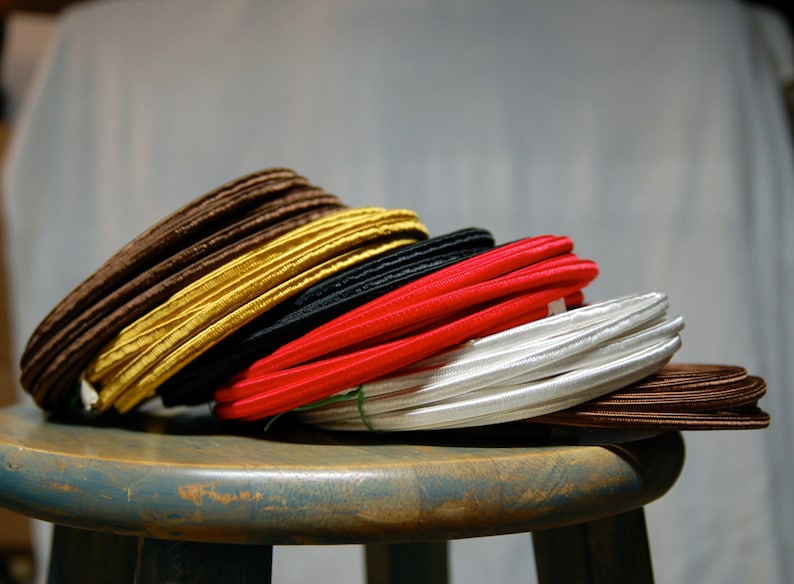 May include: A stack of different colored cords, including brown, yellow, black, red, white, and brown. The cords are stacked on a wooden stool.