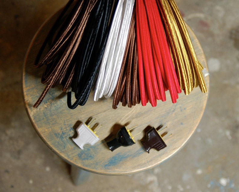 May include: Assortment of six spools of colorful electrical cord, including brown, black, white, red, gold, and a white plug with three prongs.