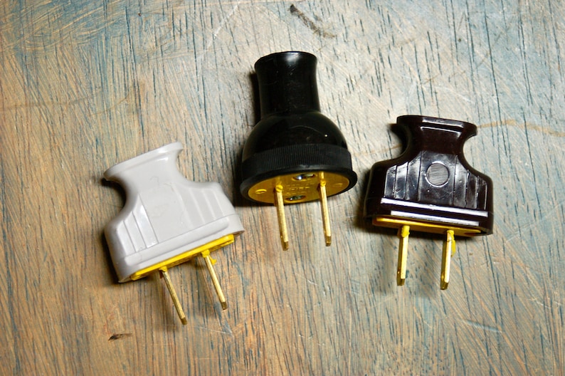 May include: Three electrical plugs with different colored plastic housings: white, black, and brown. The plugs have two prongs each, and the prongs are gold colored.