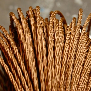 May include: A close-up of a bundle of brown twisted electrical cord.