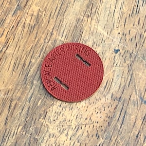 May include: A red round sticker with the text "REPLACE AFTER WIRING" in white lettering. The sticker has two holes in it.