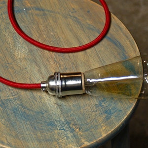 May include: A red electrical cord with a chrome light bulb socket and a clear glass light bulb.