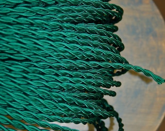 May include: A close-up of a reel of dark green twisted electrical cord.