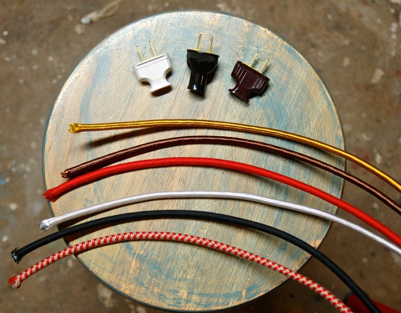 May include: Assortment of six different colored electrical cords with three different types of plugs. The cords are gold, brown, red, white, black, and red and white checkered.