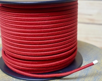 May include: A spool of red elastic cord. The cord is wound tightly around the spool and is ready to be used for crafting projects.