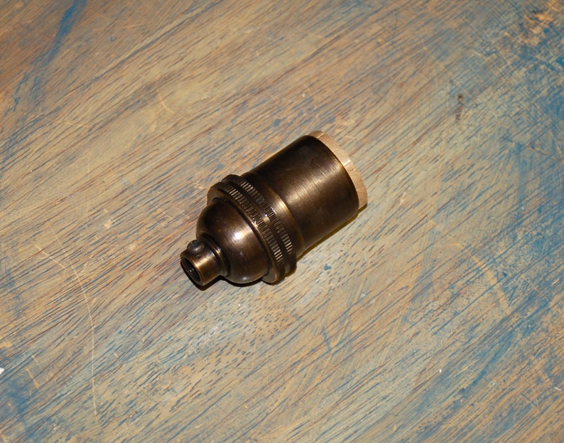 May include: A brass light bulb socket with a threaded end for attaching to a wire.