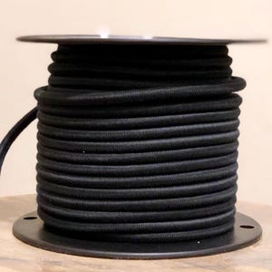 May include: A spool of black electrical cord wound around a black plastic base.