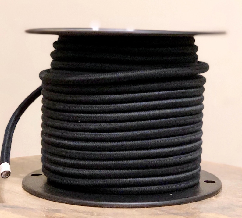 May include: A spool of black electrical cord wound around a black plastic base.