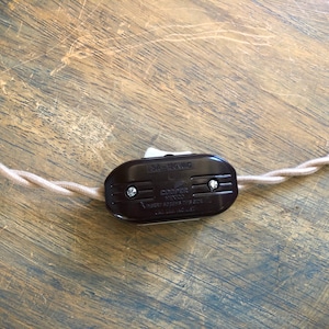 Puede incluir: Un interruptor en l&iacute;nea marr&oacute;n con un interruptor de palanca blanco. El interruptor est&aacute; etiquetado como "Cooper  15A - 120VAC  Heavy Duty Toggle Switch  Made in U.S.A."