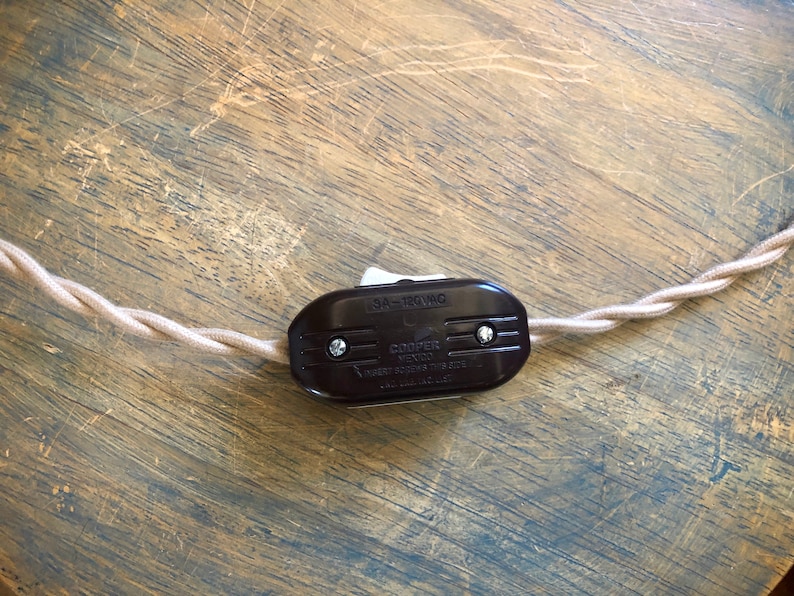 Puede incluir: Un interruptor en l&iacute;nea marr&oacute;n con un interruptor de palanca blanco. El interruptor est&aacute; etiquetado como "Cooper  15A - 120VAC  Heavy Duty Toggle Switch  Made in U.S.A."