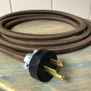 May include: Brown cloth-covered electrical cord with a black and brass grounded plug.