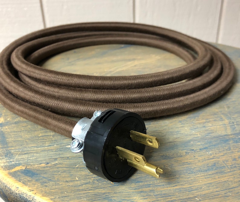 May include: Brown cloth-covered electrical cord with a black and brass grounded plug.