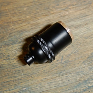 May include: A black ceramic light bulb socket with a threaded end.