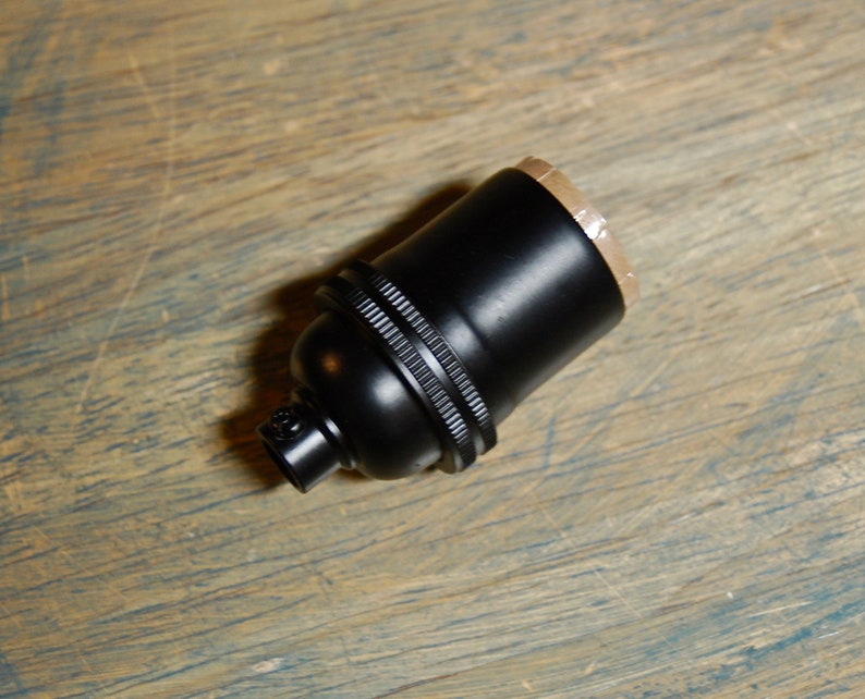 May include: A black ceramic light bulb socket with a threaded end.