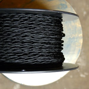 May include: A spool of black twisted cord, wound around a black plastic spool.