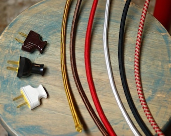 Könnte beinhalten: Sechs verschiedene Arten von Stromkabeln, darunter rot, braun, gold, weiß, schwarz und ein rot-weiß gestreiftes Kabel. Die Kabel liegen auf einer Holzoberfläche.