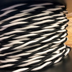 May include: Close-up of a spool of black and white twisted electrical cord.