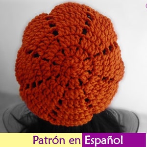 Op de afbeelding: Een gebreide beanie in een verbrand oranje kleur met een kantpatroon. De beanie is gemaakt met een dik garen en heeft een slouchy pasvorm.