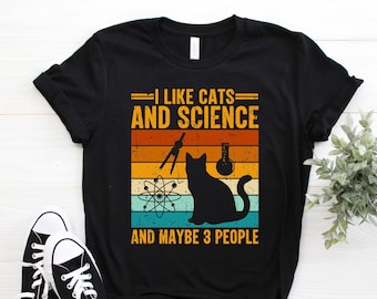 May include: Black t-shirt with a vintage-style graphic that says "I like cats and science and maybe 3 people". The graphic features a black cat, a beaker, an atom, and a compass.