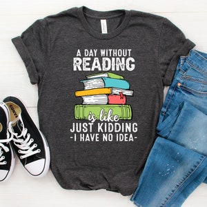 Peut inclure: Un t-shirt gris foncé avec le texte "A day without reading is like just kidding - I have no idea -" et une pile de livres colorés.