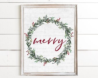 May include: A white framed print with a green wreath with red berries and the word "merry" in red cursive lettering.
