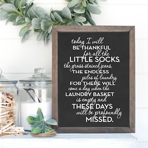 May include: A black chalkboard sign with white text that reads "today I will be thankful for all the little socks, the grass stained jeans, the endless piles of laundry, for there will come a day when the laundry basket is empty and these days will be profoundly missed."