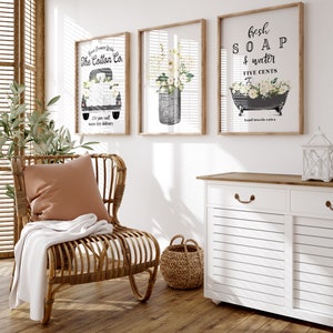 May include: Three framed prints with a farmhouse theme. The first print features a vintage truck with the text "The Cotton Co. 25&cent; per roll same day delivery". The second print features a mason jar filled with white flowers. The third print features a vintage bathtub with the text "Fresh Soap & Water Five Cents Hand towels extra".