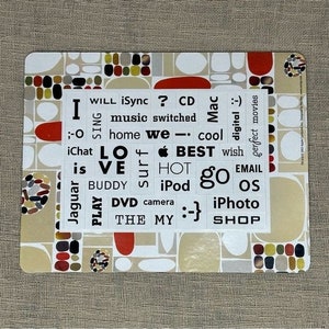 May include: A white background with a colorful pattern of circles and ovals. The background has a variety of words and phrases printed on it, including "I will iSync? CD", "music switched", "home we - cool", "iChat LO VE", "surf HOT BEST", "iPod go EMAIL", "Jaguar PLAY BUDDY", "DVD camera", "THE MY :-}", "iPhoto SHOP".