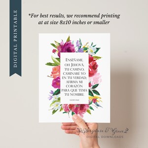 May include: A digital printable featuring a floral design with pink, purple, and white flowers. The artwork includes Spanish text from Psalms 86:11, and the words "DIGITAL PRINTABLE" are printed on the left side. The image is held by a hand.